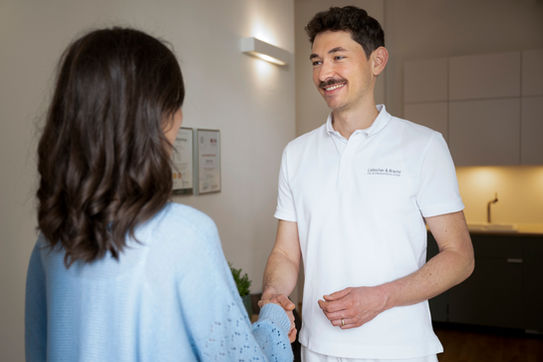 Robert Guzy begrüßt Patientin in der Praxis Wien